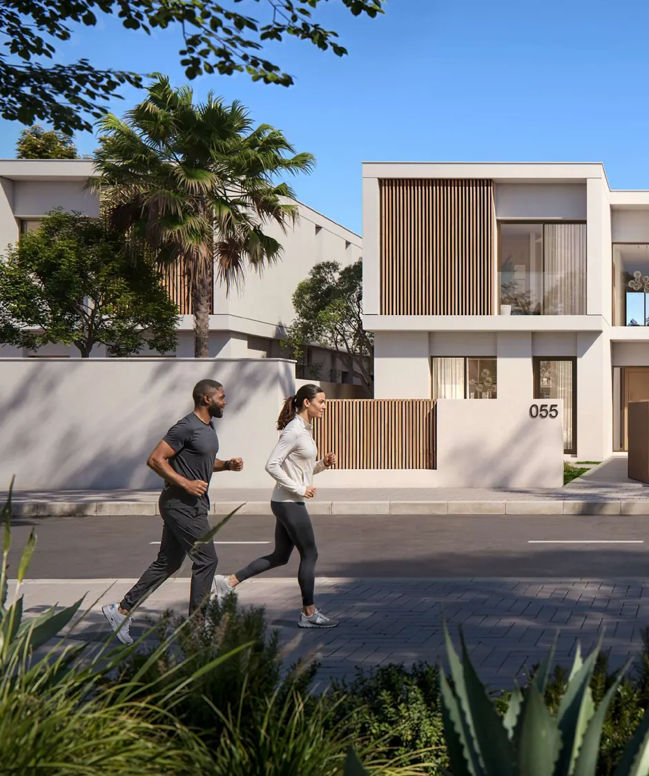 Two residents jog past timber-screened villas on a tree-lined street